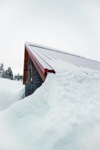 Snow-covered roof with thick ice buildup along the eaves and icicles hanging over a gutter.