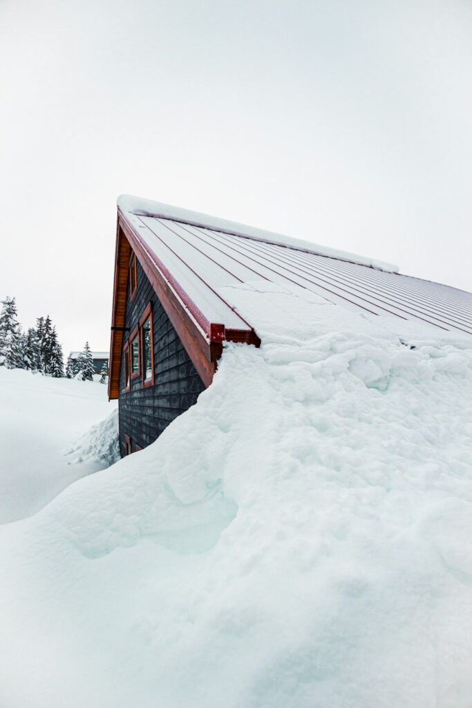 Snow-covered roof with thick ice buildup along the eaves and icicles hanging over a gutter.
